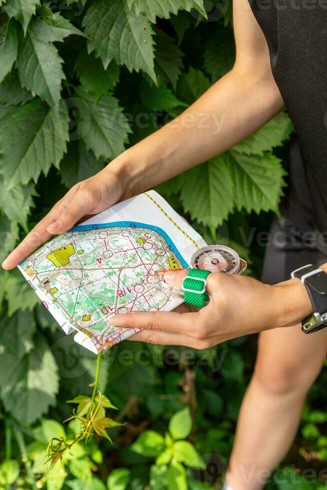Frau halten ein Karte und das Kompass während Orientierungslauf Wettbewerbe. foto