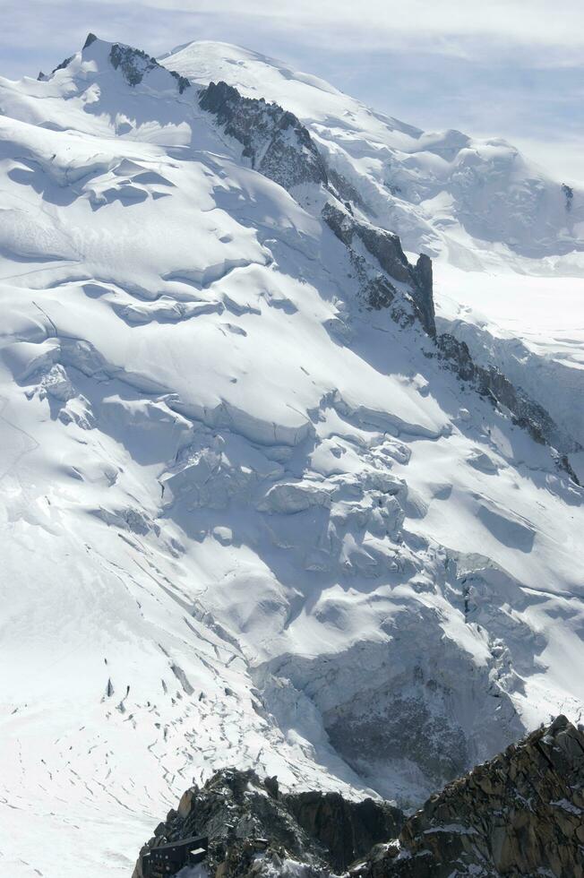zwei Menschen sind Wandern oben ein Berg mit Schnee bedeckt Berge foto