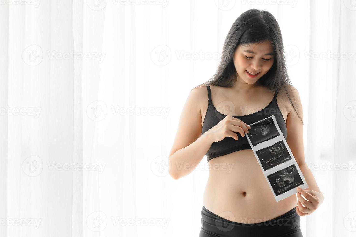 zwei Monate asiatische schwangere Frau, die Ultraschalluntersuchung hält foto
