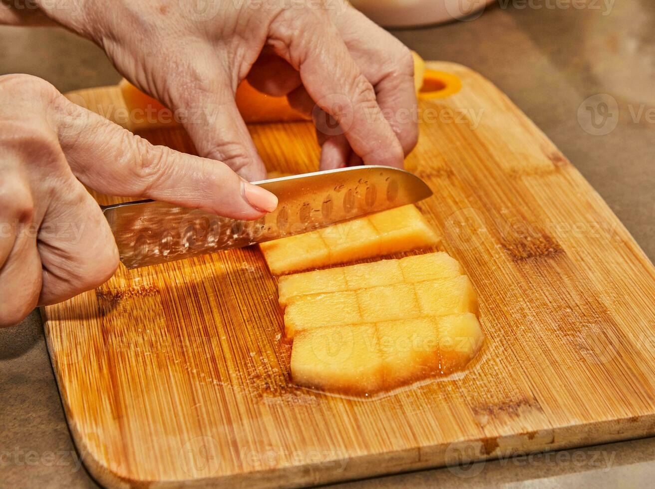 Koch schneidet Melone in Würfel auf hölzern Tafel im das Küche foto