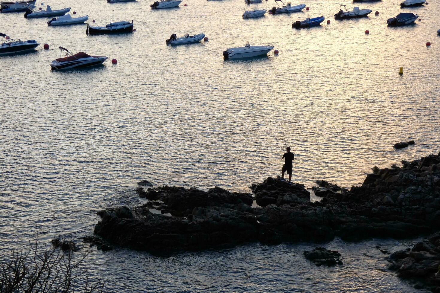 Mann von hinten beleuchtet mit ein Angeln Stange im das Meer foto