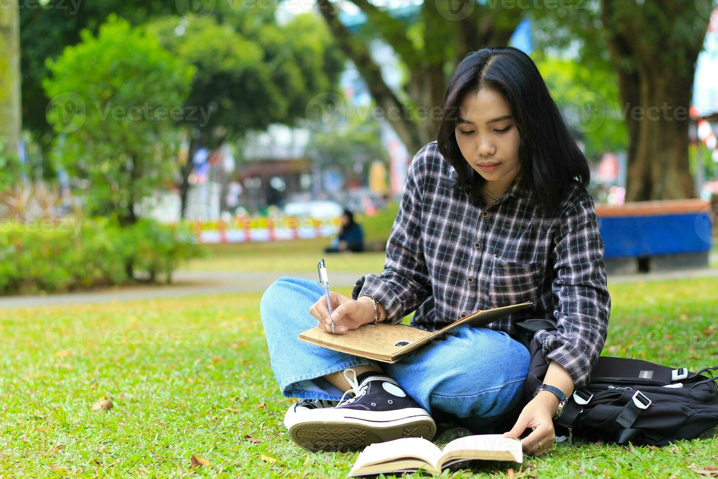 lächelnd asiatisch schön jung Frau genießen Schreiben zu tun aufführen und Idee im Notizbuch im draußen Stadt Park foto