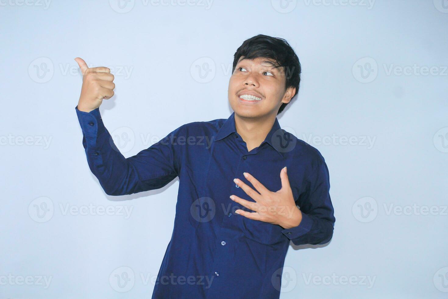 stolz jung asiatisch Mann lächelnd mit dankbar Gesicht zum überlebt von Herz Attacke und hat Wiederherstellung ist halten Truhe mit donnert oben tragen Marine Hemd foto