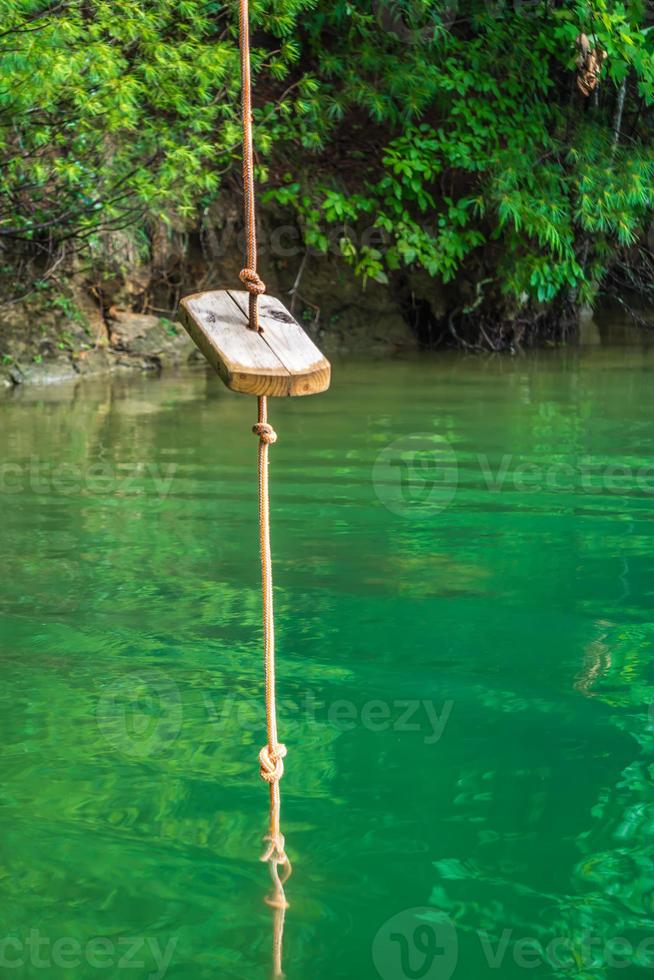 Seilschaukel über klarem Wassersee in den Bergen foto