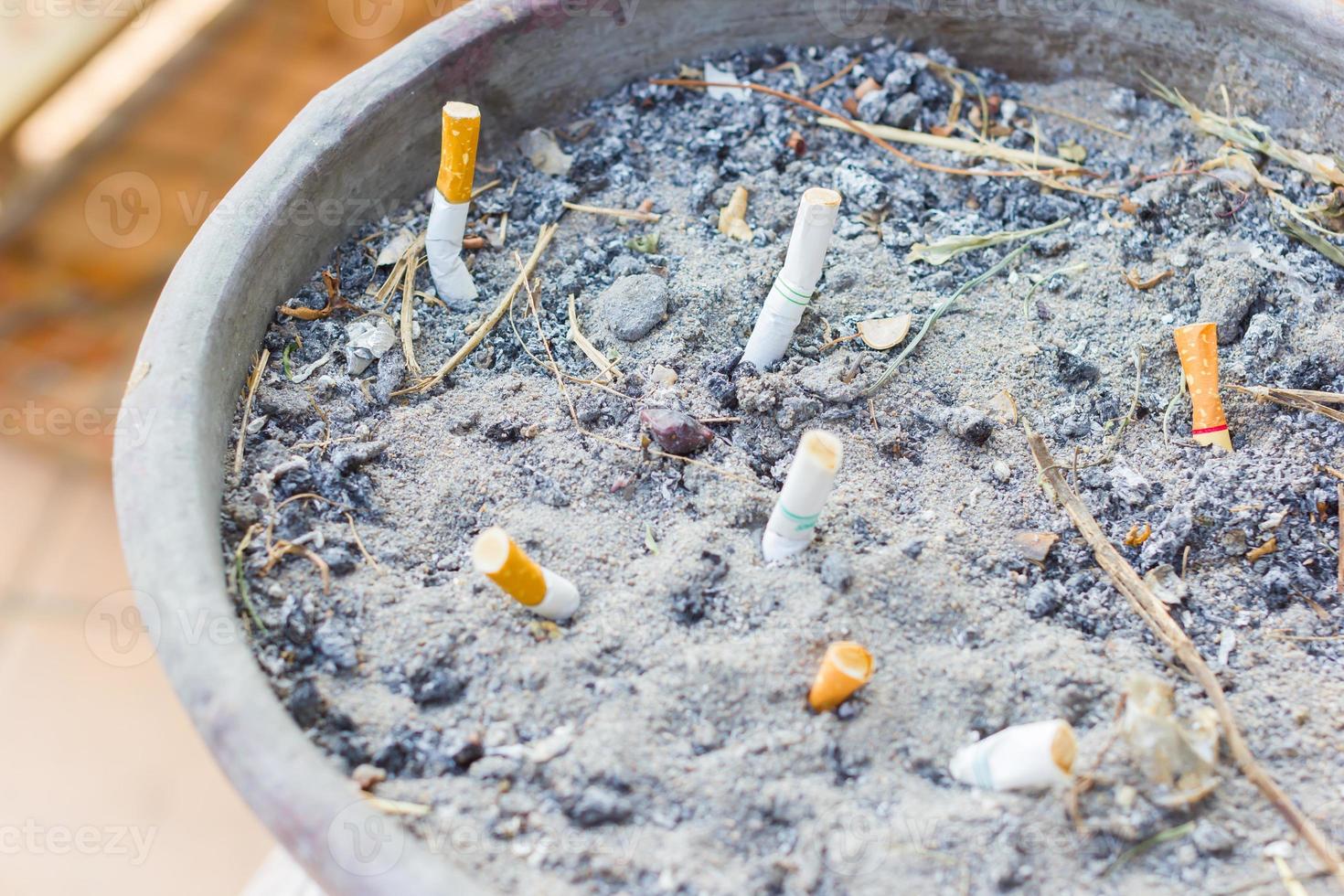 gerauchte Zigarettenkippen in einem öffentlichen Aschenbecher, selektiver Fokus foto