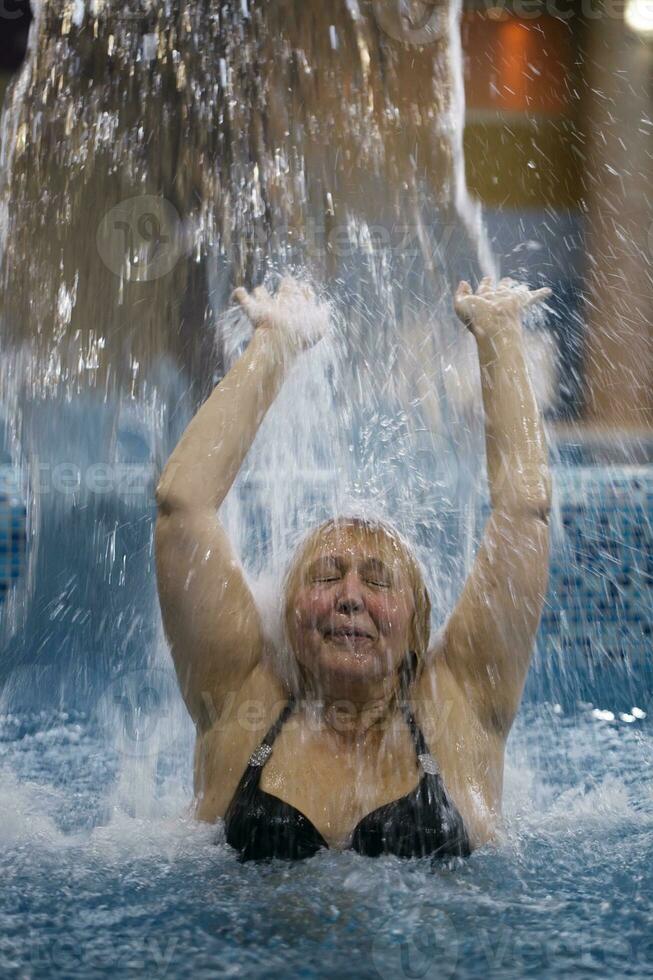 Frau planschen im ein Schwimmbad unter ein Jet von Wasser foto