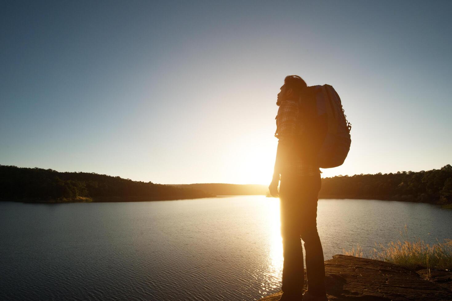 Silhouette des Wanderers mit Rucksack im Sonnenuntergangslandschaftsberg. foto