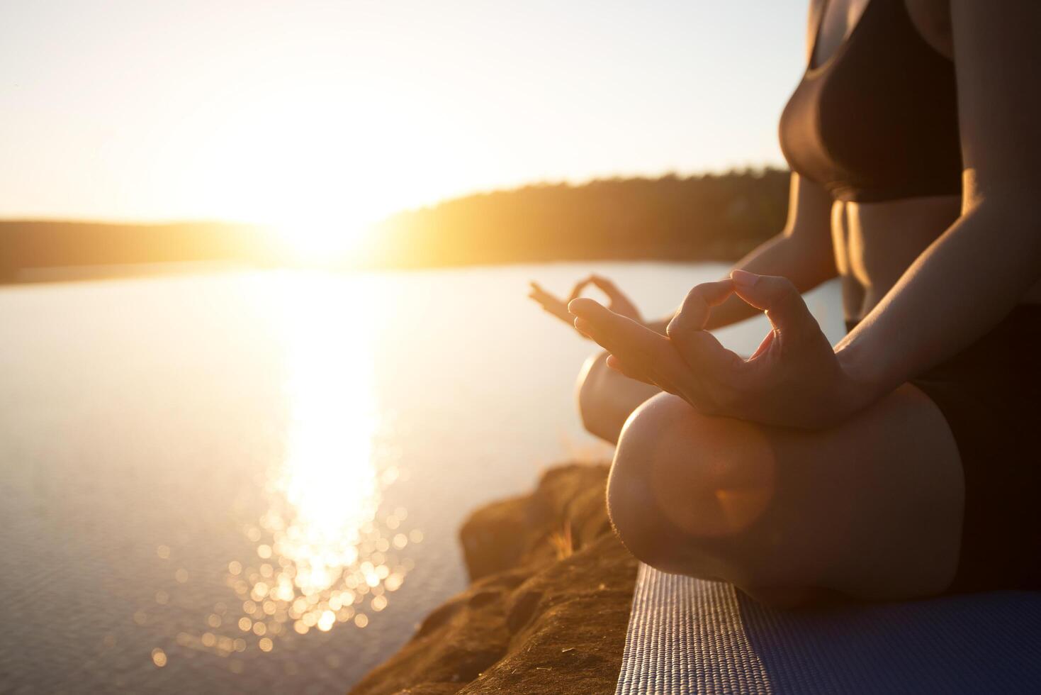 Junge gesunde Frau praktiziert Yoga am Bergsee während des Sonnenuntergangs. foto