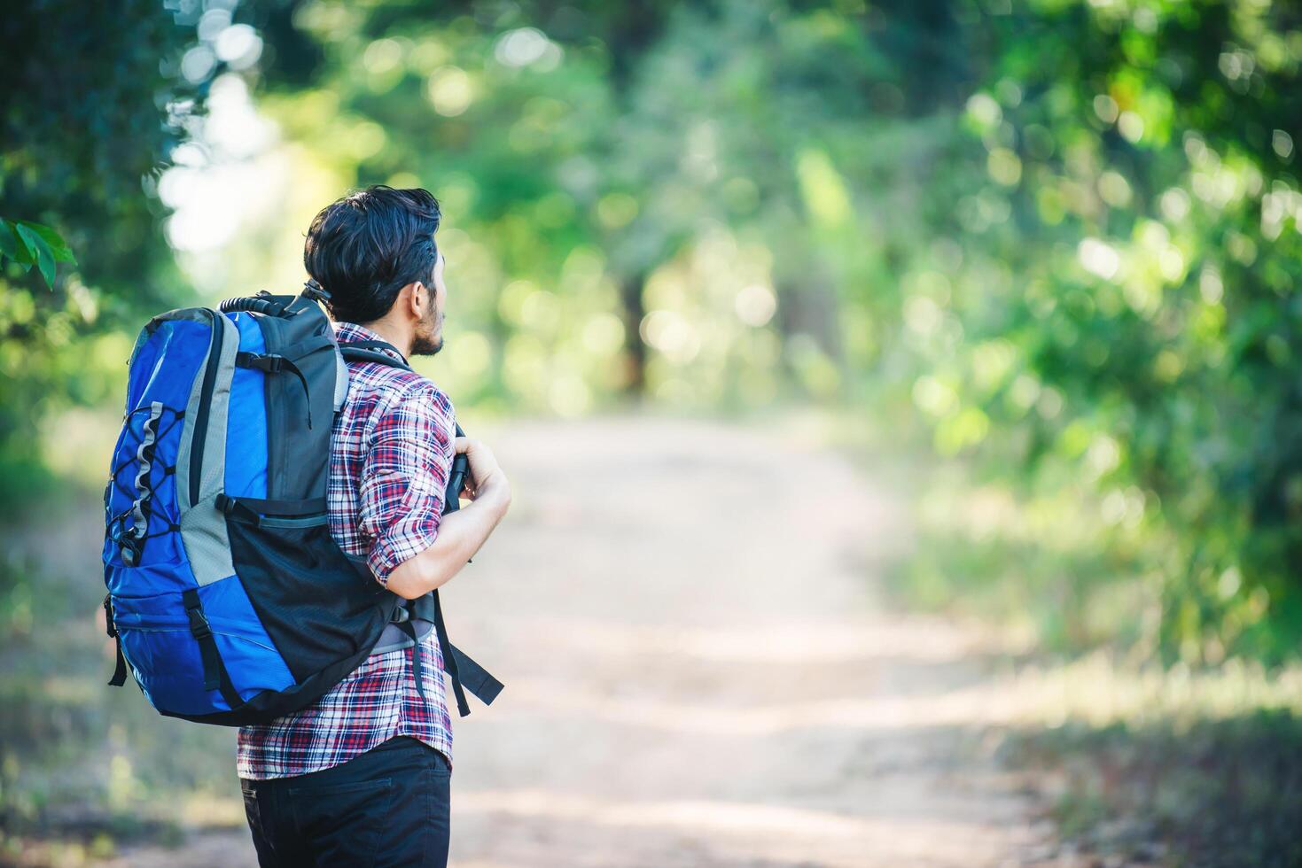 junger Hipster-Mann zu Fuß auf der Landstraße bei Wanderungen im Urlaub. foto