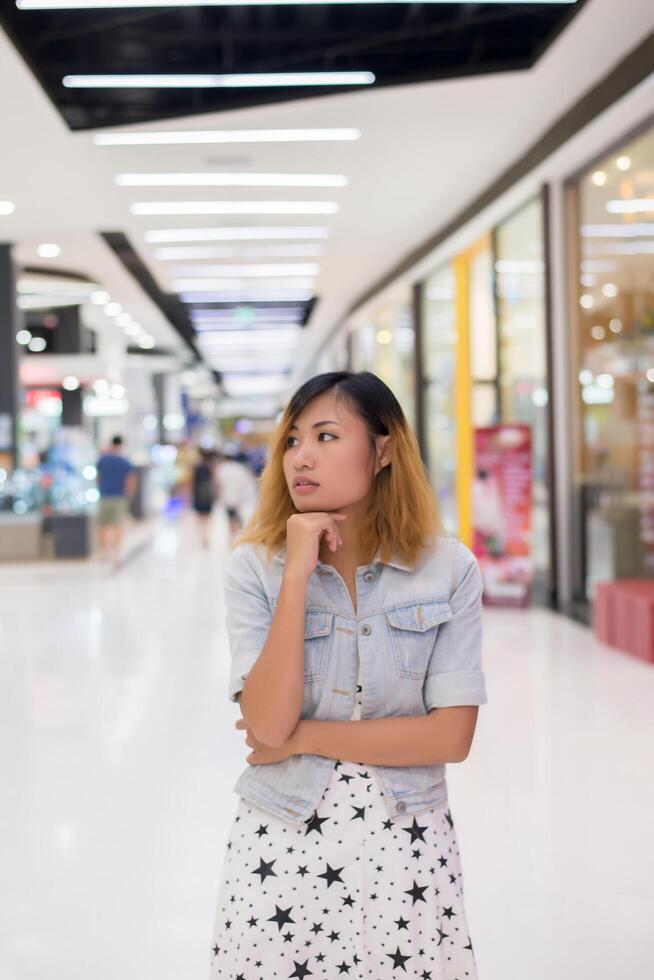 junge schöne Frau, die etwas im Einkaufszentrum denkt. foto