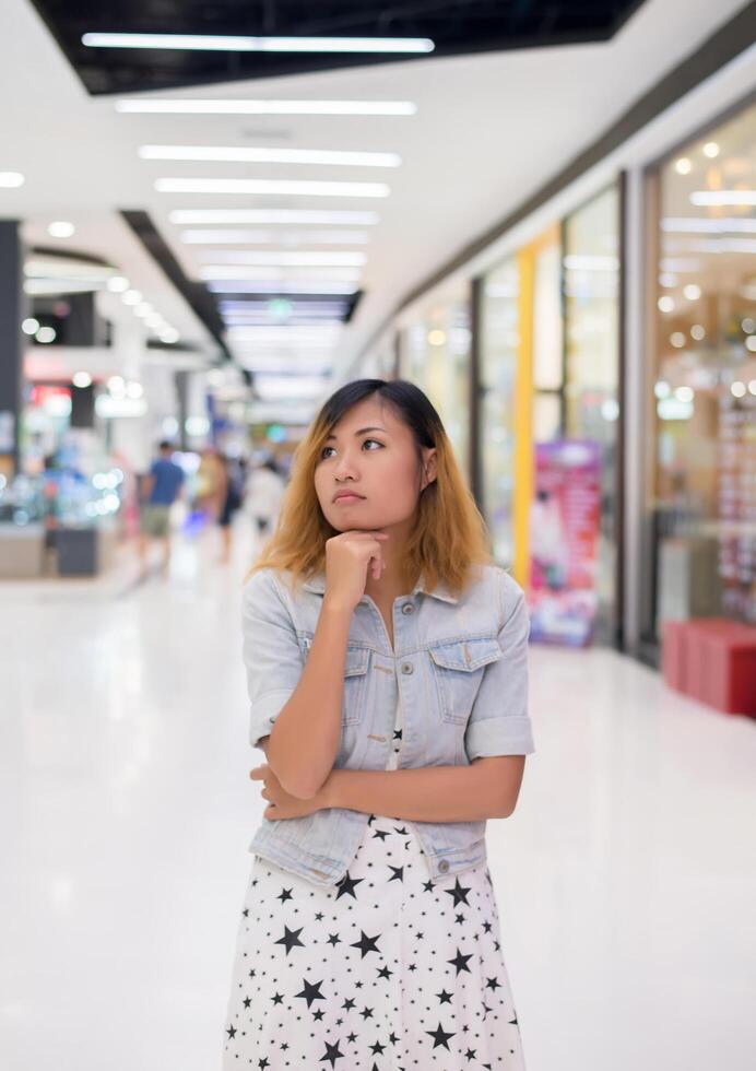 junge schöne Frau, die etwas im Einkaufszentrum denkt. foto