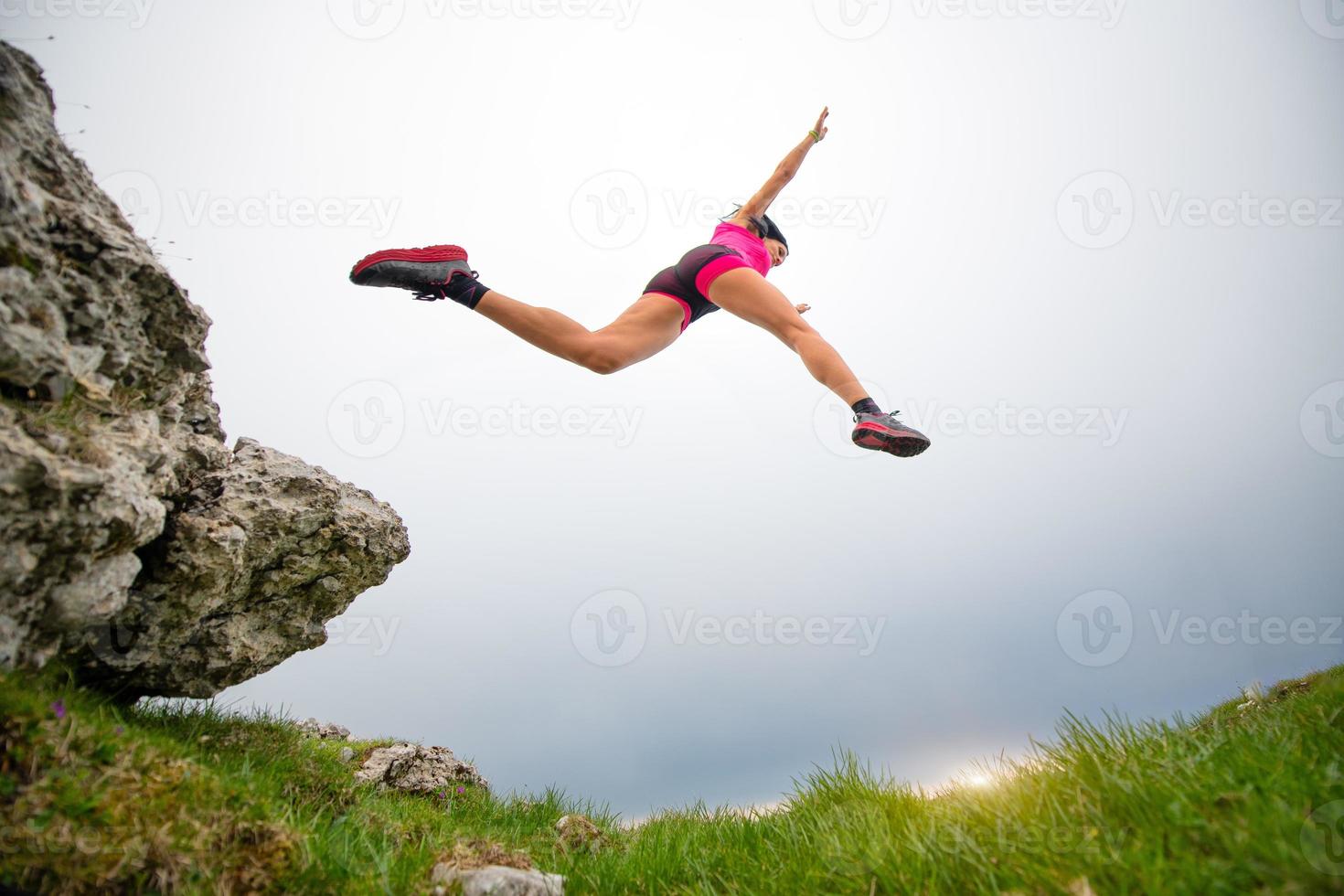 Sprung einer sportlichen Sportlerin, die in den Bergen läuft foto