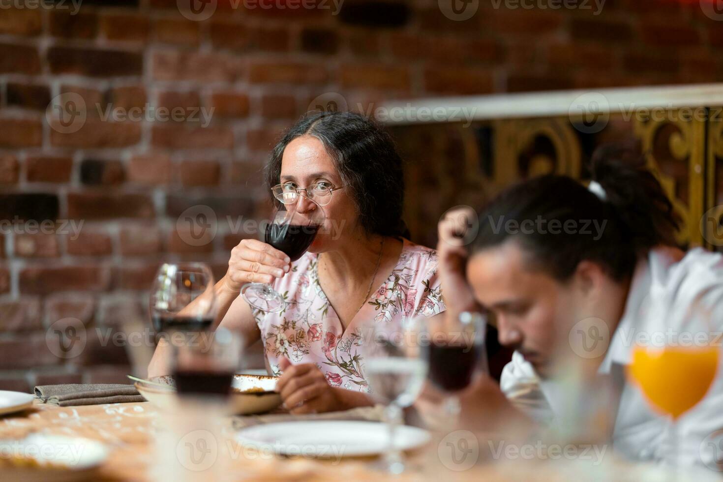 Frau haben ein Glas von Wein beim Familie Feier im Restaurant foto