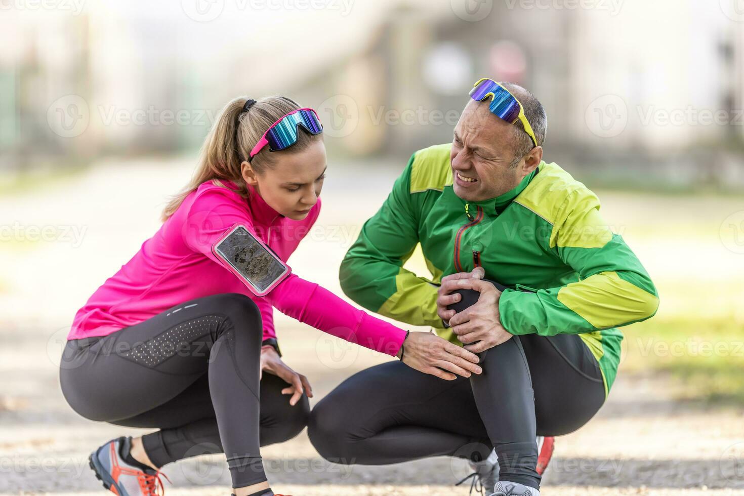 ein reifen des Mannes Knie Schmerzen nach Laufen ist gegeben zuerst Hilfe durch ein jung weiblich Läufer foto