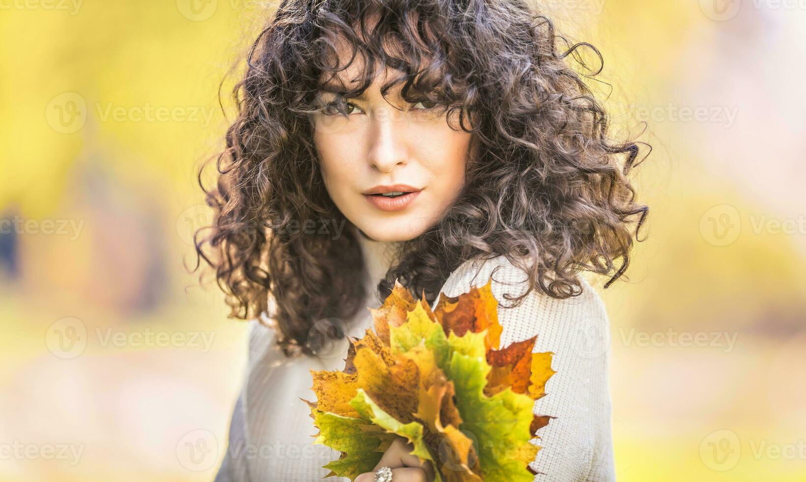 Herbst Porträt von jung Frau mit lockig Haar und Strauß von Ahorn Blätter foto