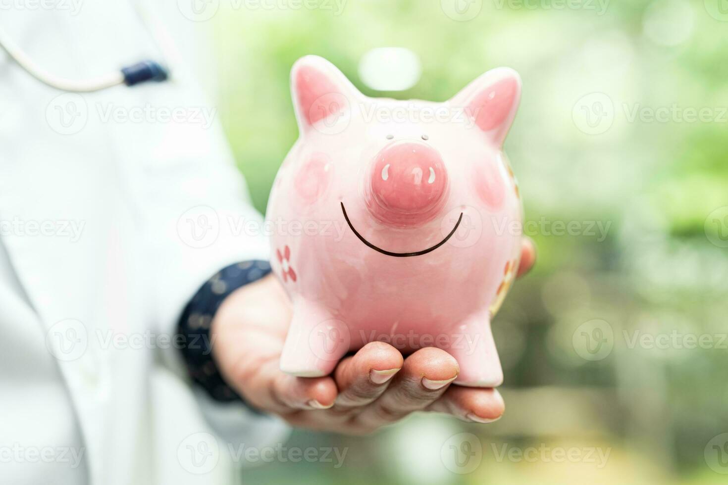 Arzt mit Stethoskop halten Schweinchen Bank zum Speichern Geld Gesundheit Pflege kosten, medizinisch finanziell. foto