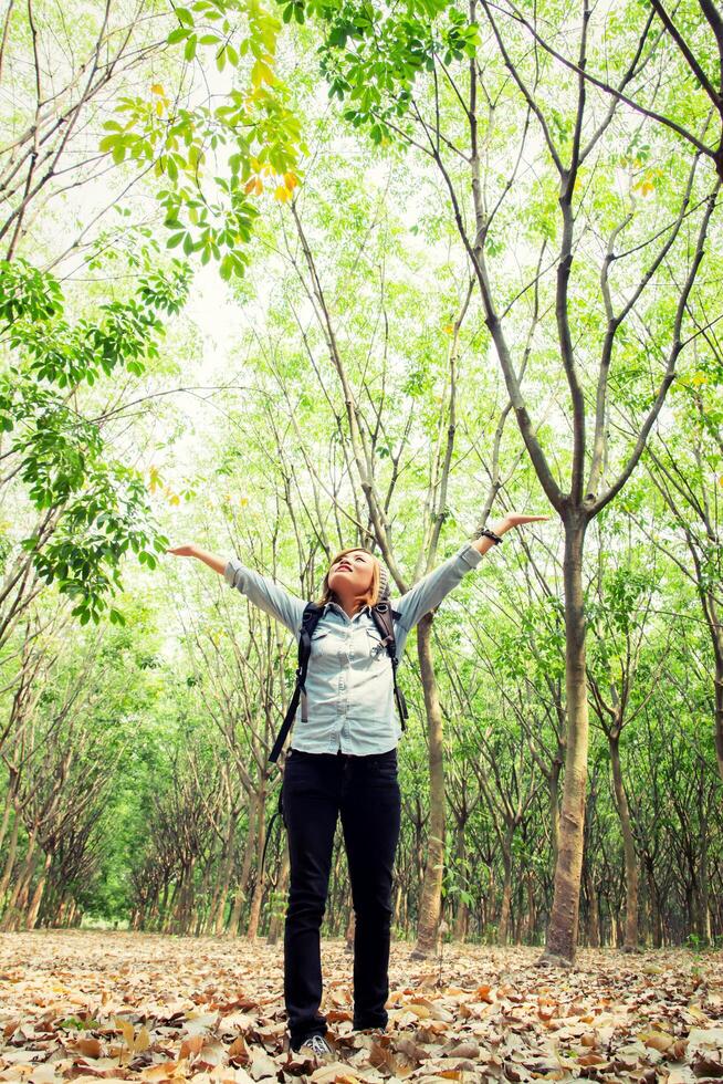 junge Frau, die im Wald spazieren geht und ihre Hände glücklich mit frischer Luft anhebt. foto