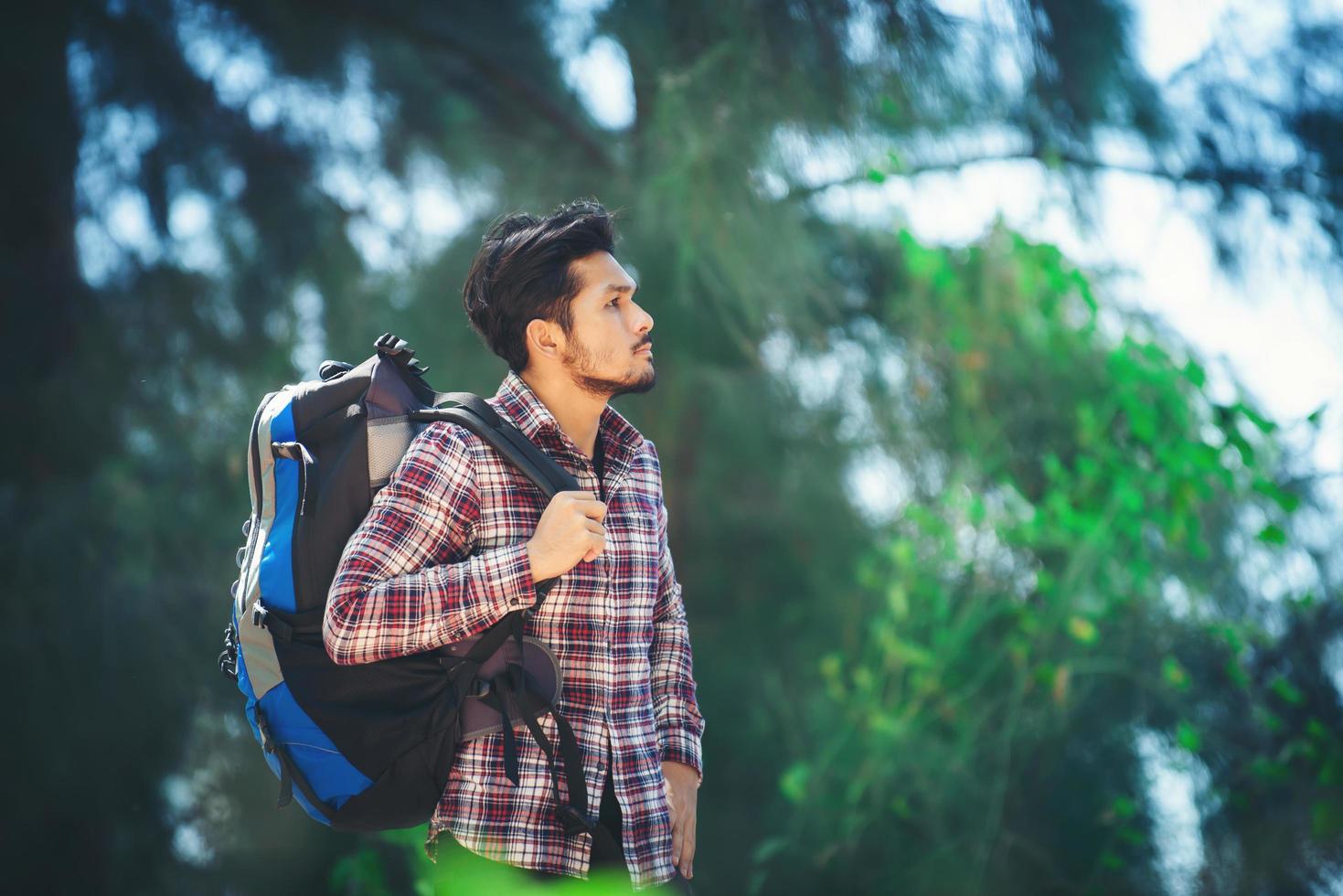 Wanderer Mann entspannt sich mit einem großen Rucksack beim Spaziergang im Wald. foto
