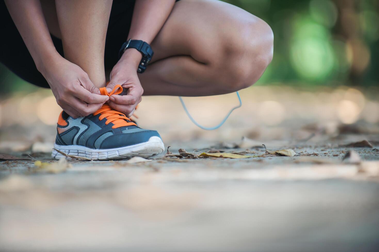 Junge Fitness-Frau sitzt binden ihre Schuhe, bevor sie joggen geht. foto