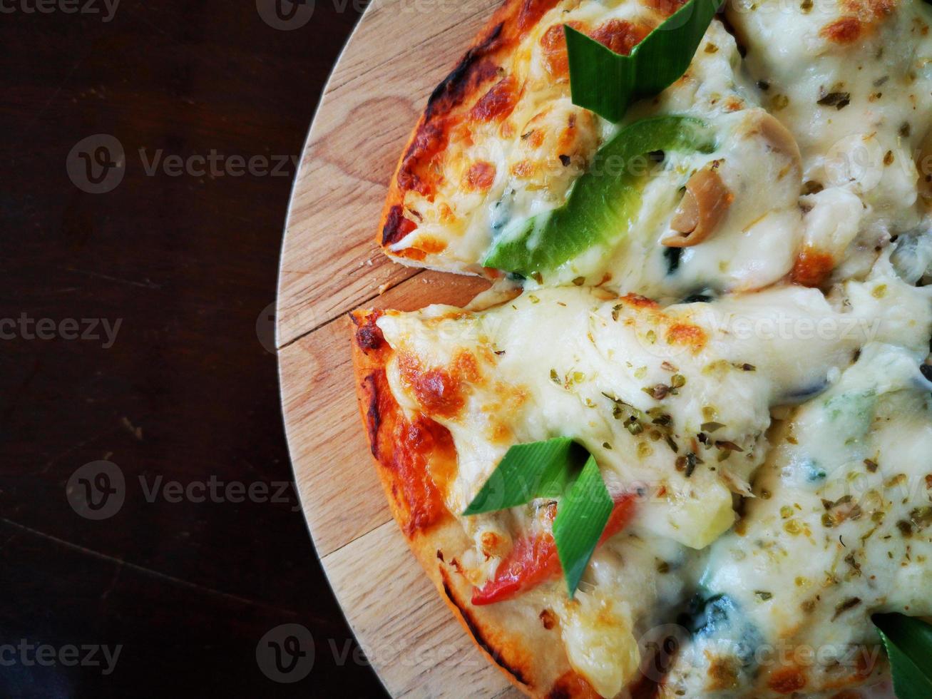 Nahaufnahmepizza auf Holzplatte mit dunkelbraunem Exemplar. foto