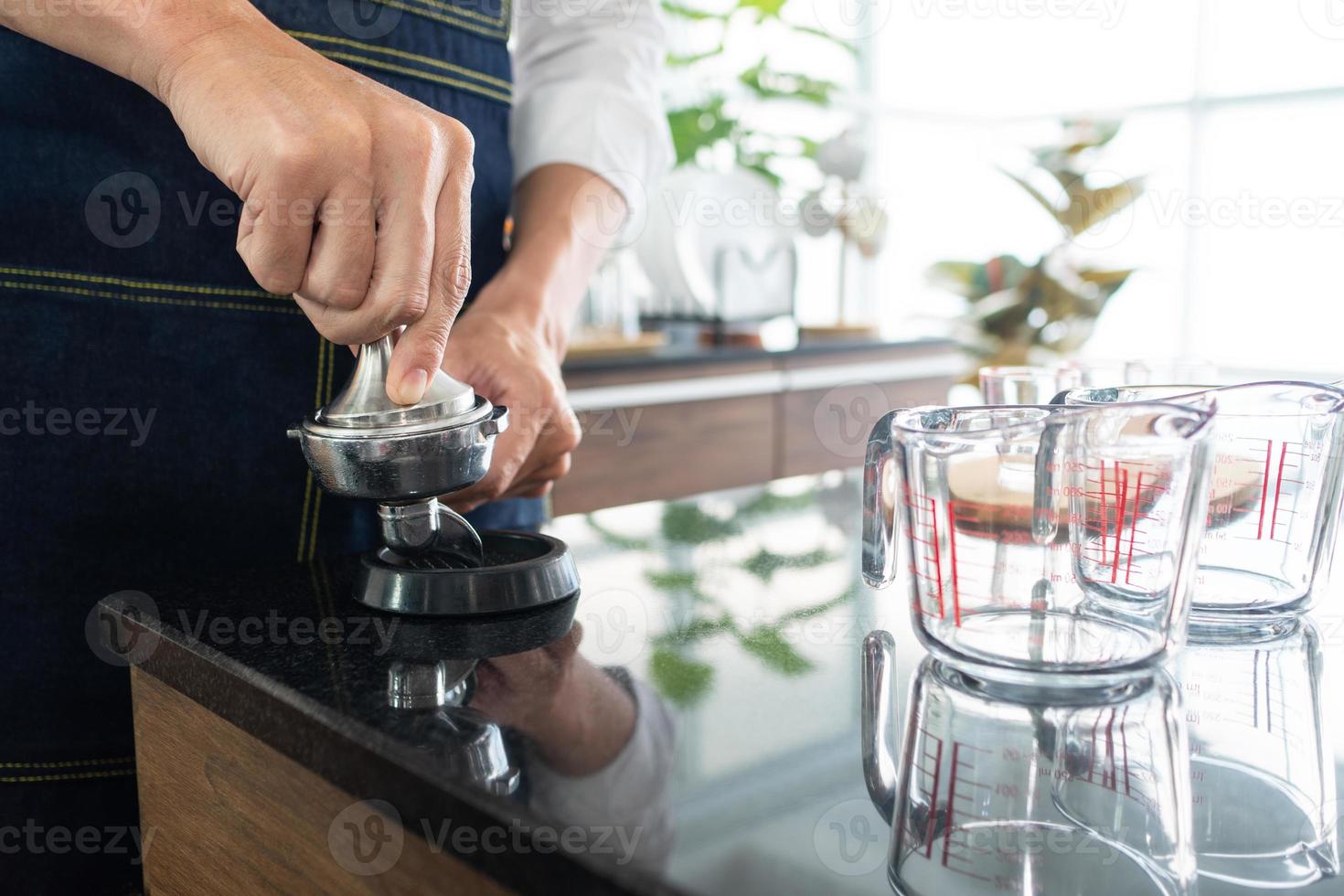 Barista mit Kaffeemühlenmaschine, um Kaffeebohnen im Café zu grillen foto