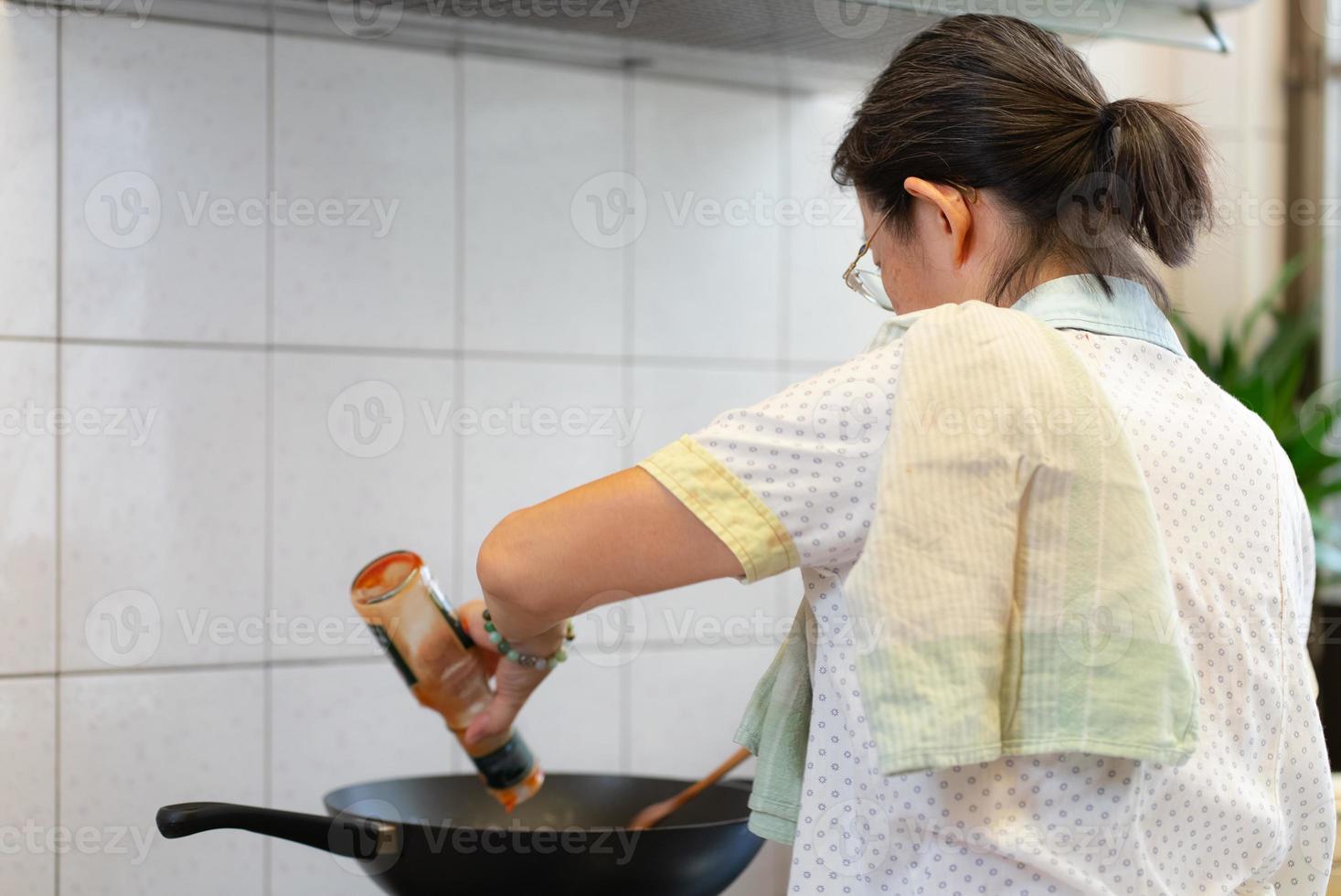Senior asiatische Frau, die Pasta zum Mittagessen in der Küche kocht foto