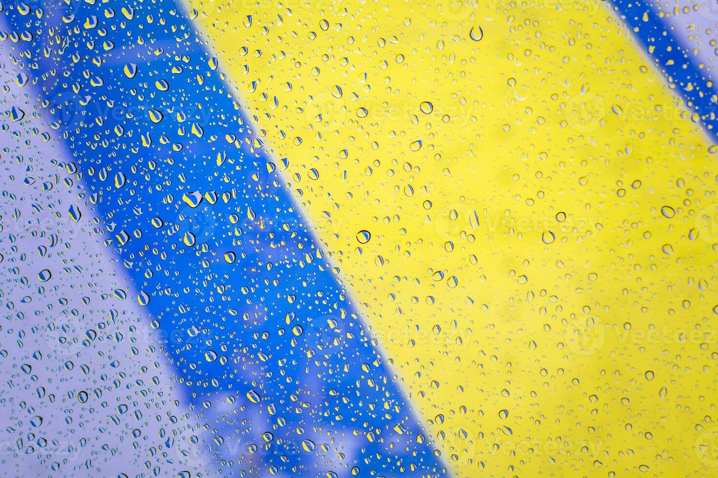 gotas de lluvia con Fondo de Bandera de Ukraine, gotas de lluvia schlimmer vidrio con Farben de Bandera de Ukraine. gotas de agua en la Ventana schlimmer Fondo de vidrio foto