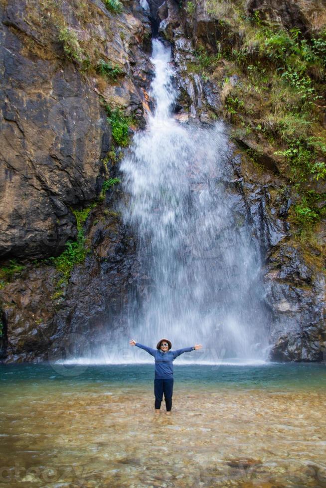 Frau steht vor schönem Wasserfall. foto