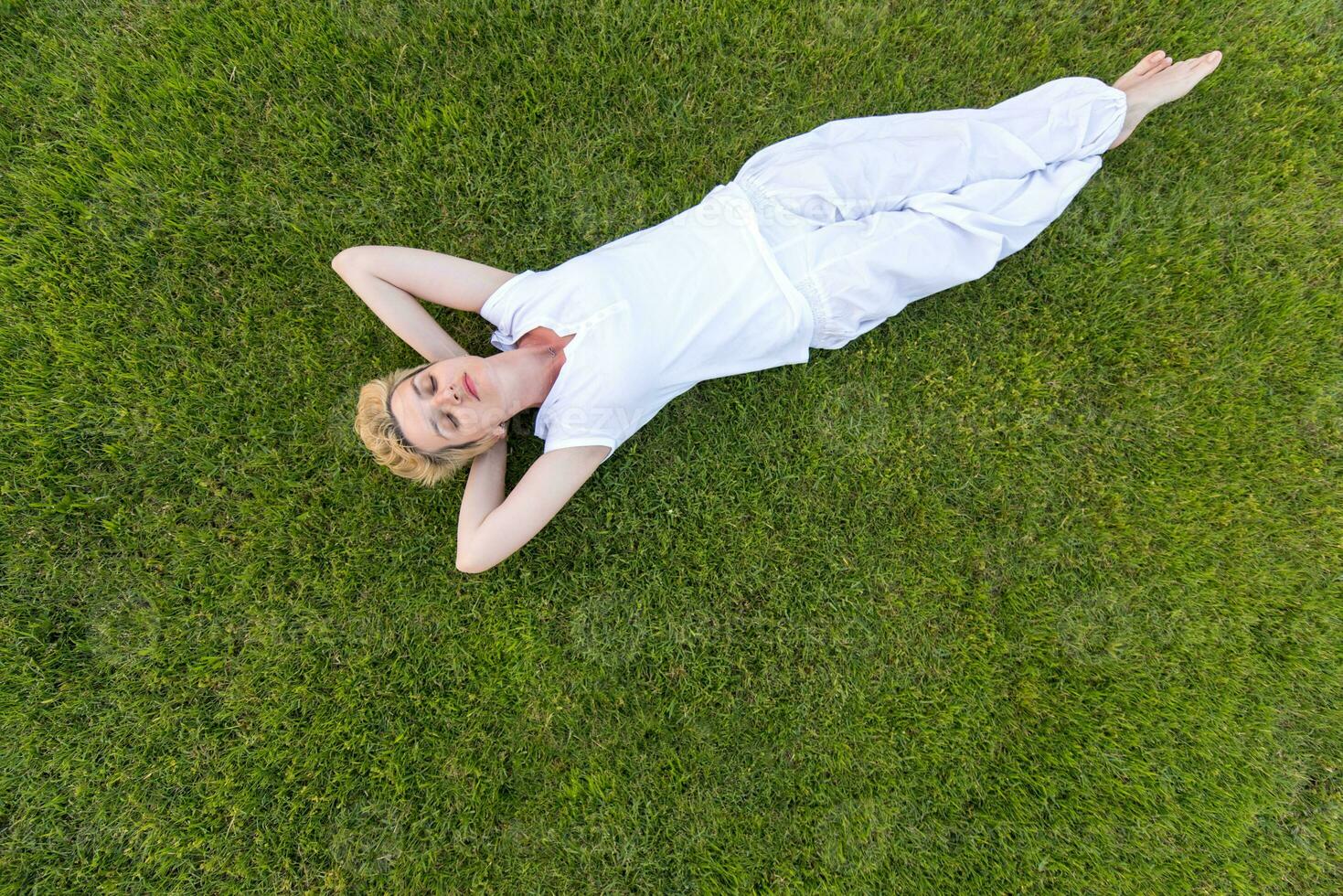 Draufsicht der jungen Frau, die auf dem Gras sich entspannt foto