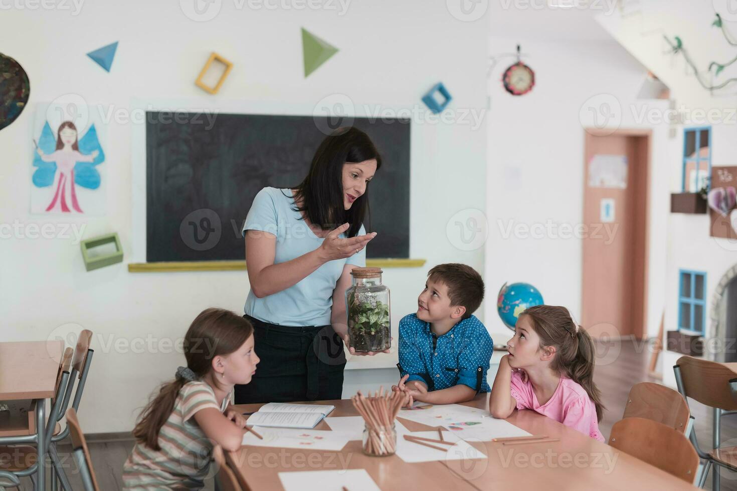 weiblich Lehrer mit Kinder im Biologie Klasse beim elementar Schule Dirigieren Biologie oder botanisch wissenschaftlich Experiment Über nachhaltig wachsend Pflanzen. Lernen Über Pflanzen im ein Glas Krug foto