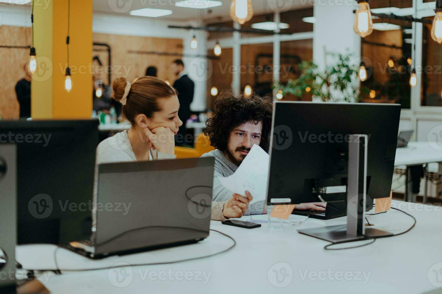 zwei Kollegen Arbeiten auf ein Projekt im modern Anfang Büros. Kerl mit afro Haarschnitt und ein weiblich blond Mitarbeiter Arbeiten beim das Büro. foto