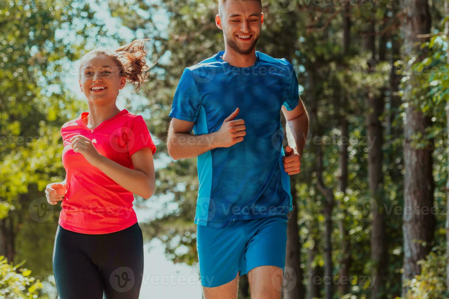 Paar genießen im ein gesund Lebensstil während Joggen auf ein Land Straße durch das schön sonnig Wald, Übung und Fitness Konzept foto