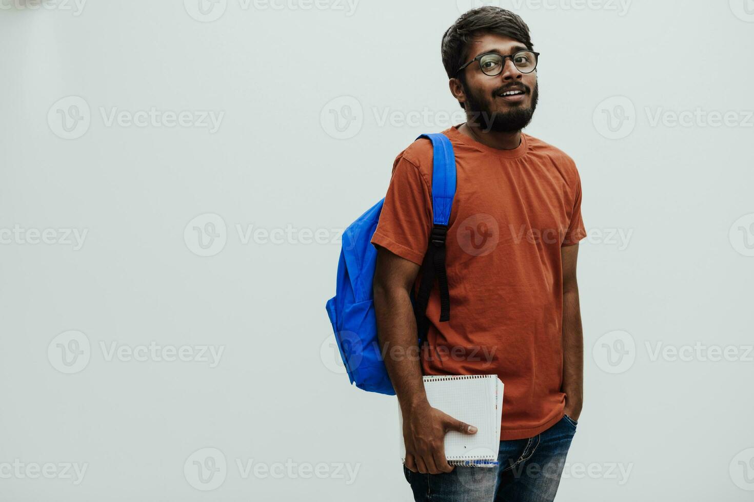 indisch Schüler mit Blau Rucksack, Brille und Notizbuch posieren auf grau Hintergrund. das Konzept von Bildung und Schulung. Zeit zu gehen zurück zu Schule foto