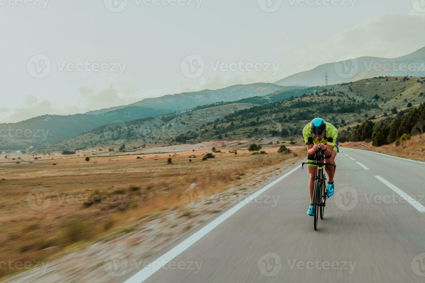 voll Länge Porträt von ein aktiv Triathlet im Sportbekleidung und mit ein schützend Helm Reiten ein Fahrrad. selektiv Fokus foto