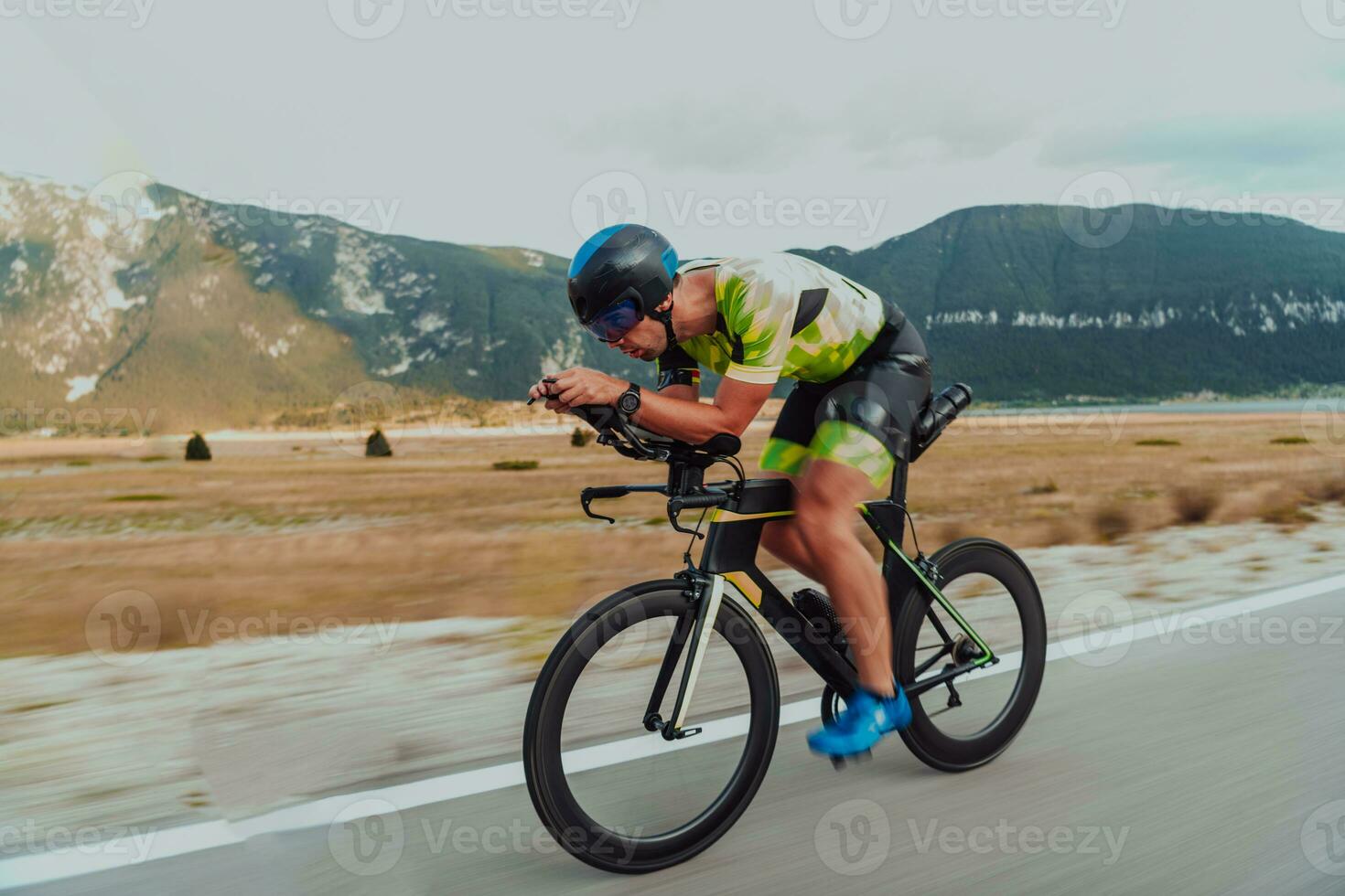 voll Länge Porträt von ein aktiv Triathlet im Sportbekleidung und mit ein schützend Helm Reiten ein Fahrrad. selektiv Fokus foto