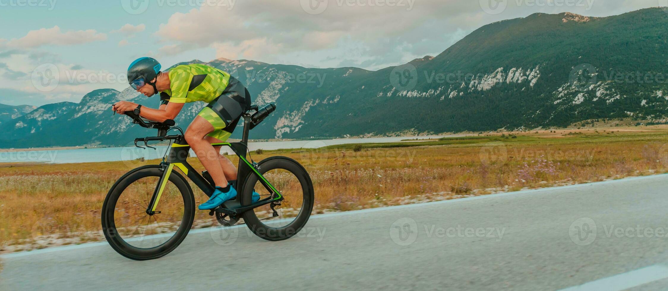 voll Länge Porträt von ein aktiv Triathlet im Sportbekleidung und mit ein schützend Helm Reiten ein Fahrrad. selektiv Fokus foto