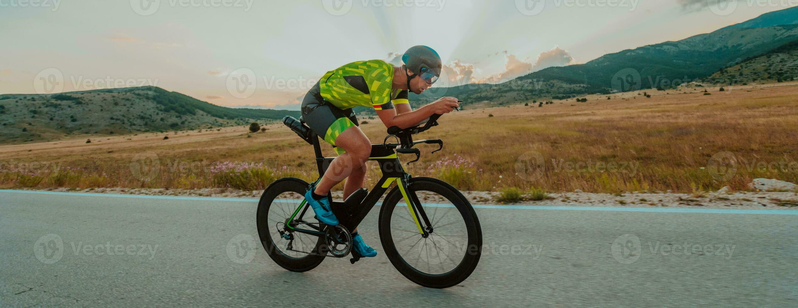 voll Länge Porträt von ein aktiv Triathlet im Sportbekleidung und mit ein schützend Helm Reiten ein Fahrrad. selektiv Fokus foto