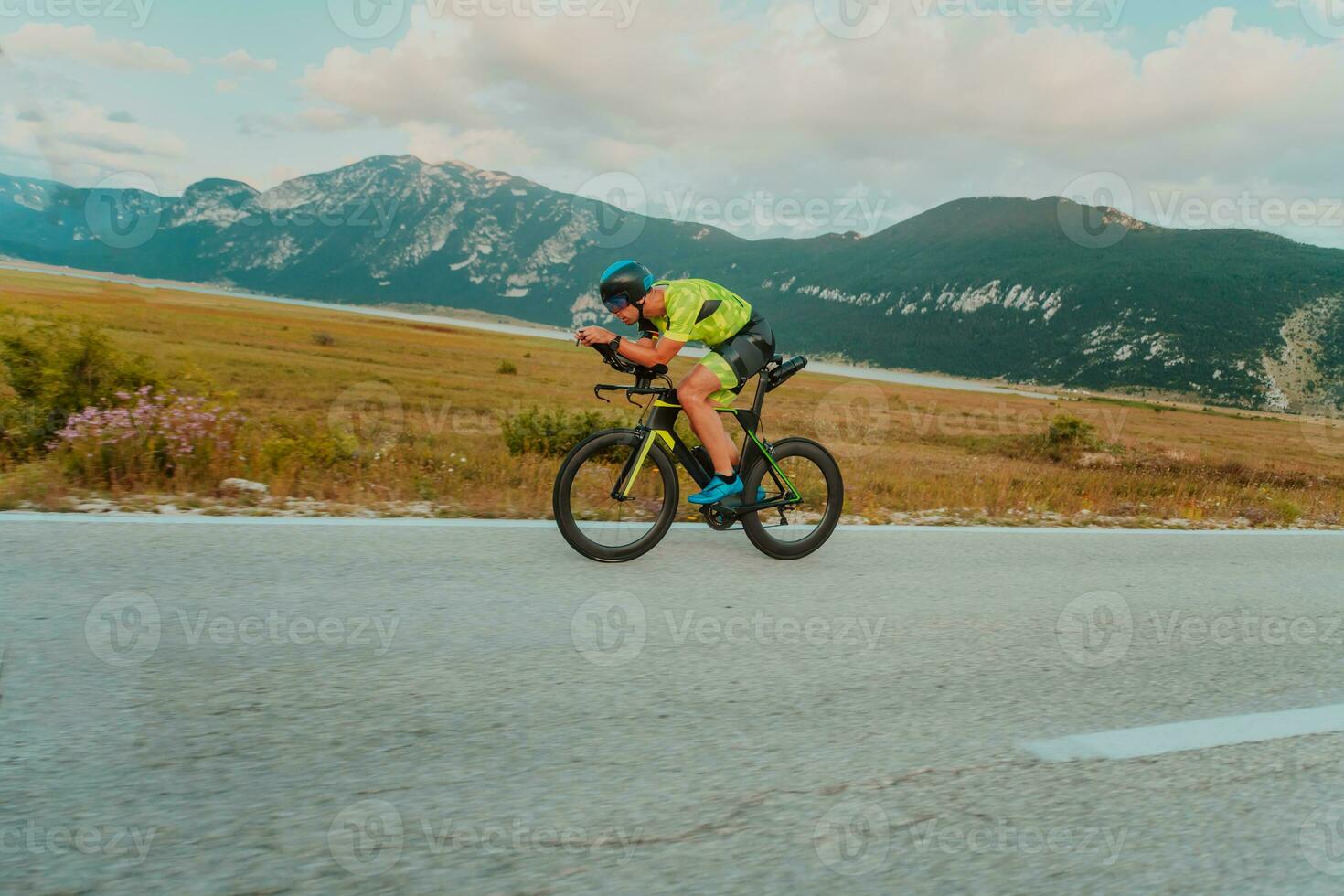 voll Länge Porträt von ein aktiv Triathlet im Sportbekleidung und mit ein schützend Helm Reiten ein Fahrrad. selektiv Fokus foto