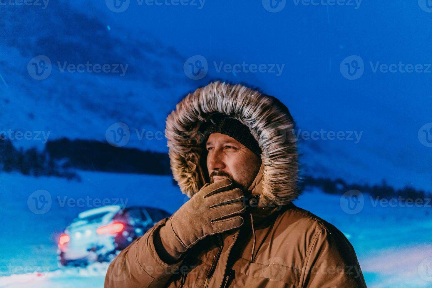 Kopf Schuss von ein Mann im ein kalt schneebedeckt Bereich tragen ein dick braun Winter Jacke, Schnee Brille und Handschuhe auf ein kalt skandinavisch Nacht. Leben im das kalt Regionen von das Land. foto