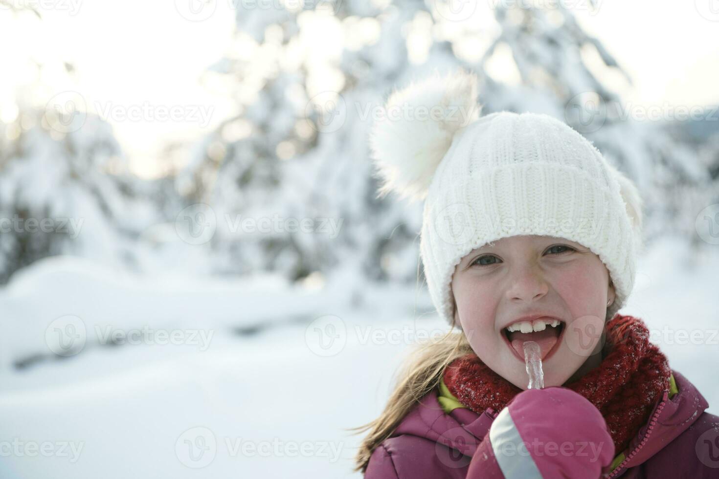 süßes kleines Mädchen beim Essen von Eiszapfen an einem schönen Wintertag foto