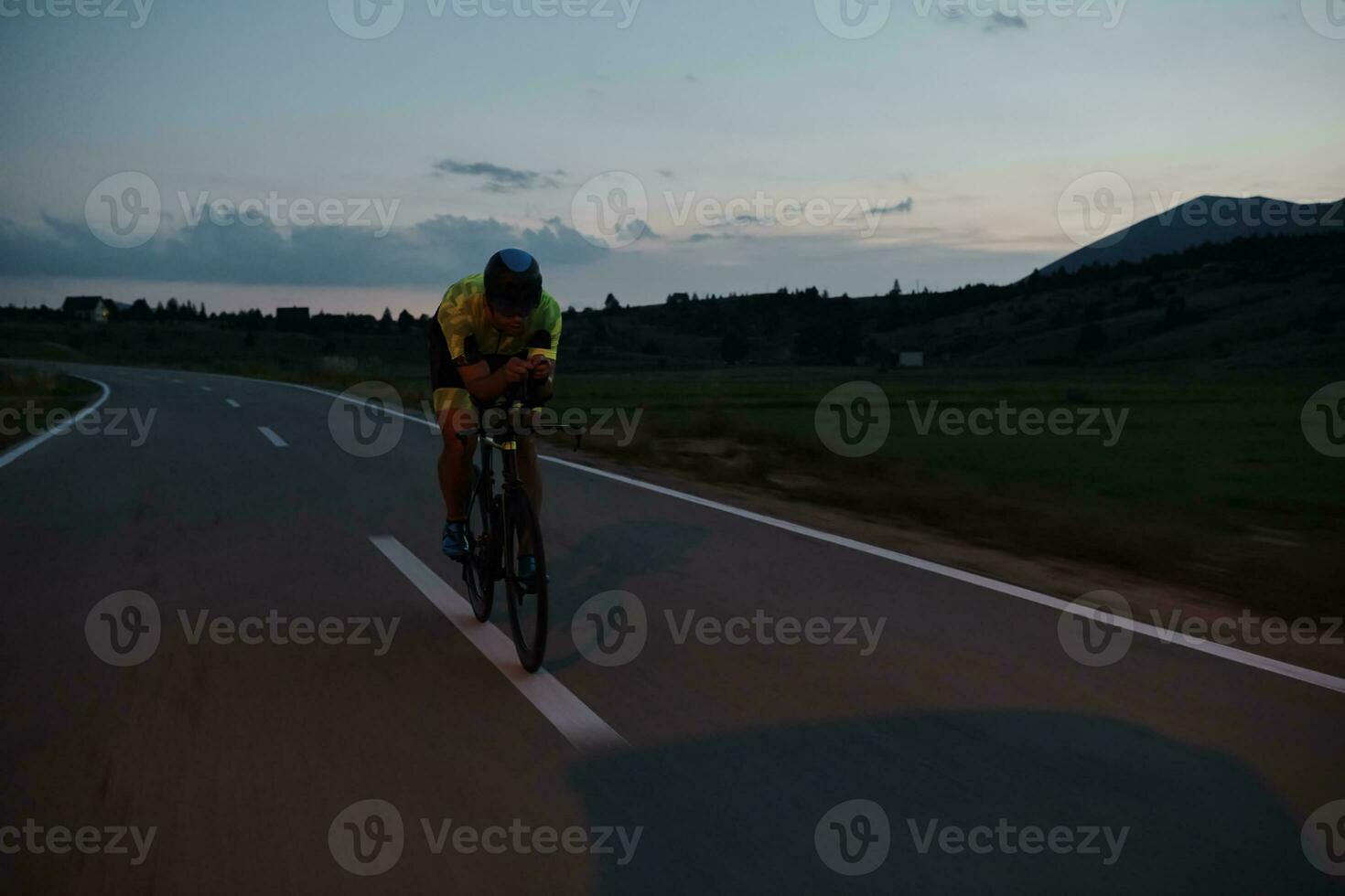 Triathlon-Athlet, der nachts Fahrrad fährt foto