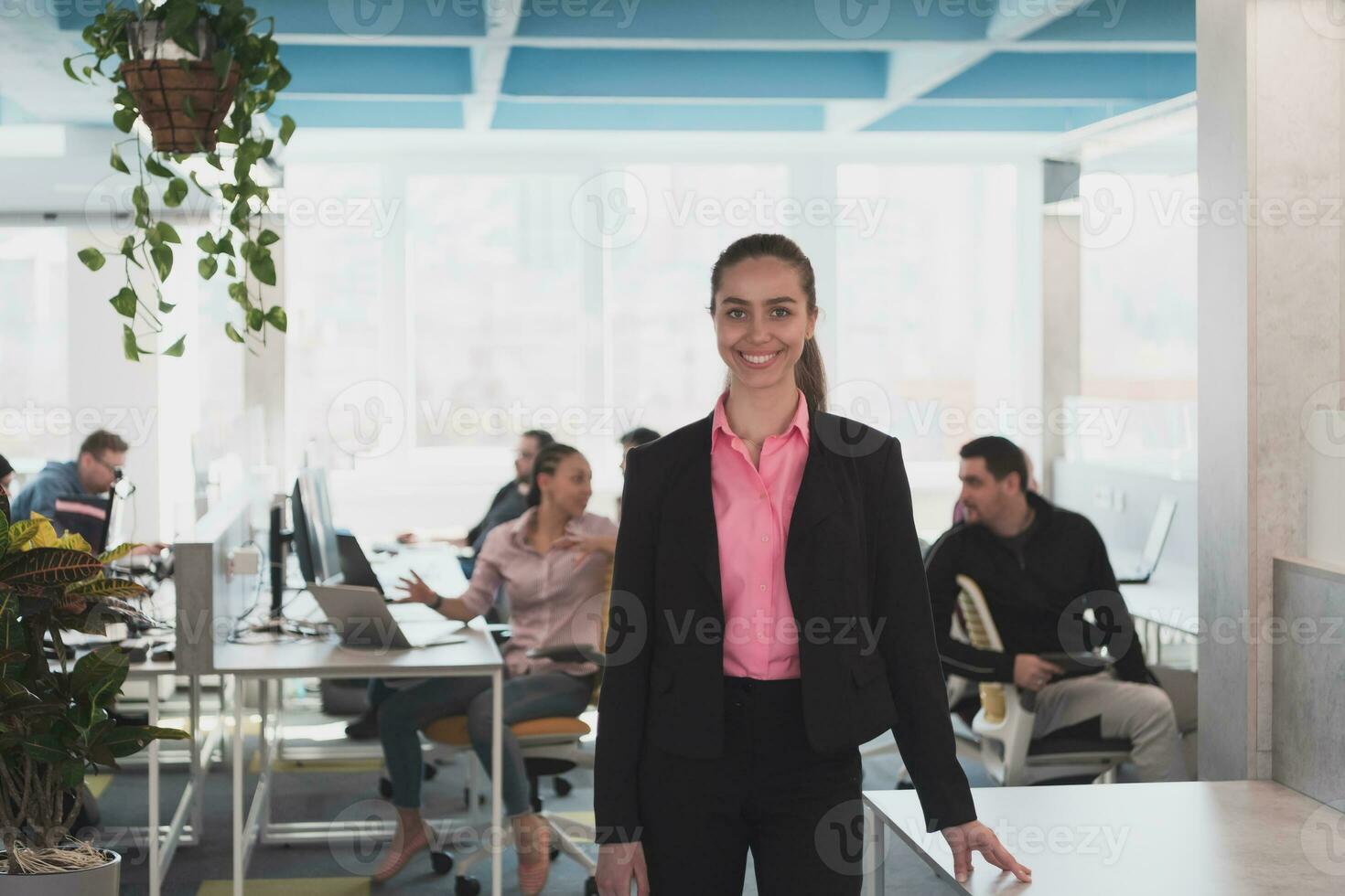 Porträt von jung lächelnd Geschäft Frau im kreativ öffnen Raum Coworking Anfang Büro. erfolgreich Geschäftsfrau im modern Büro. Mannschaft von Mitarbeiter Arbeiten im Hintergrund. foto