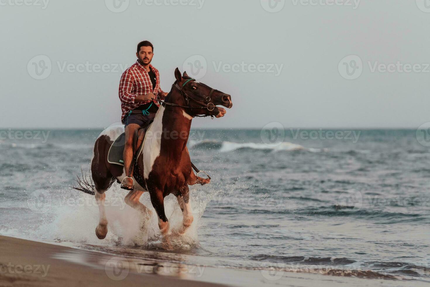 ein moderner mann in sommerkleidung genießt es, bei sonnenuntergang an einem schönen sandstrand zu reiten. selektiver Fokus foto