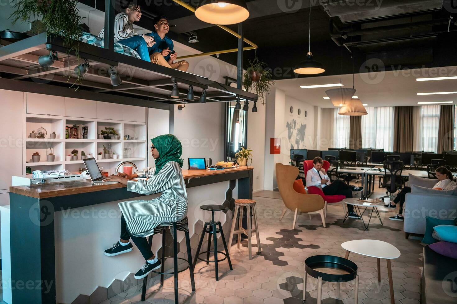 Gruppe lässiger multiethnischer Geschäftsleute, die eine Pause von der Arbeit machen und verschiedene Dinge tun, während sie ihre Freizeit im Entspannungsbereich eines modernen Großraum-Startup-Büros genießen foto