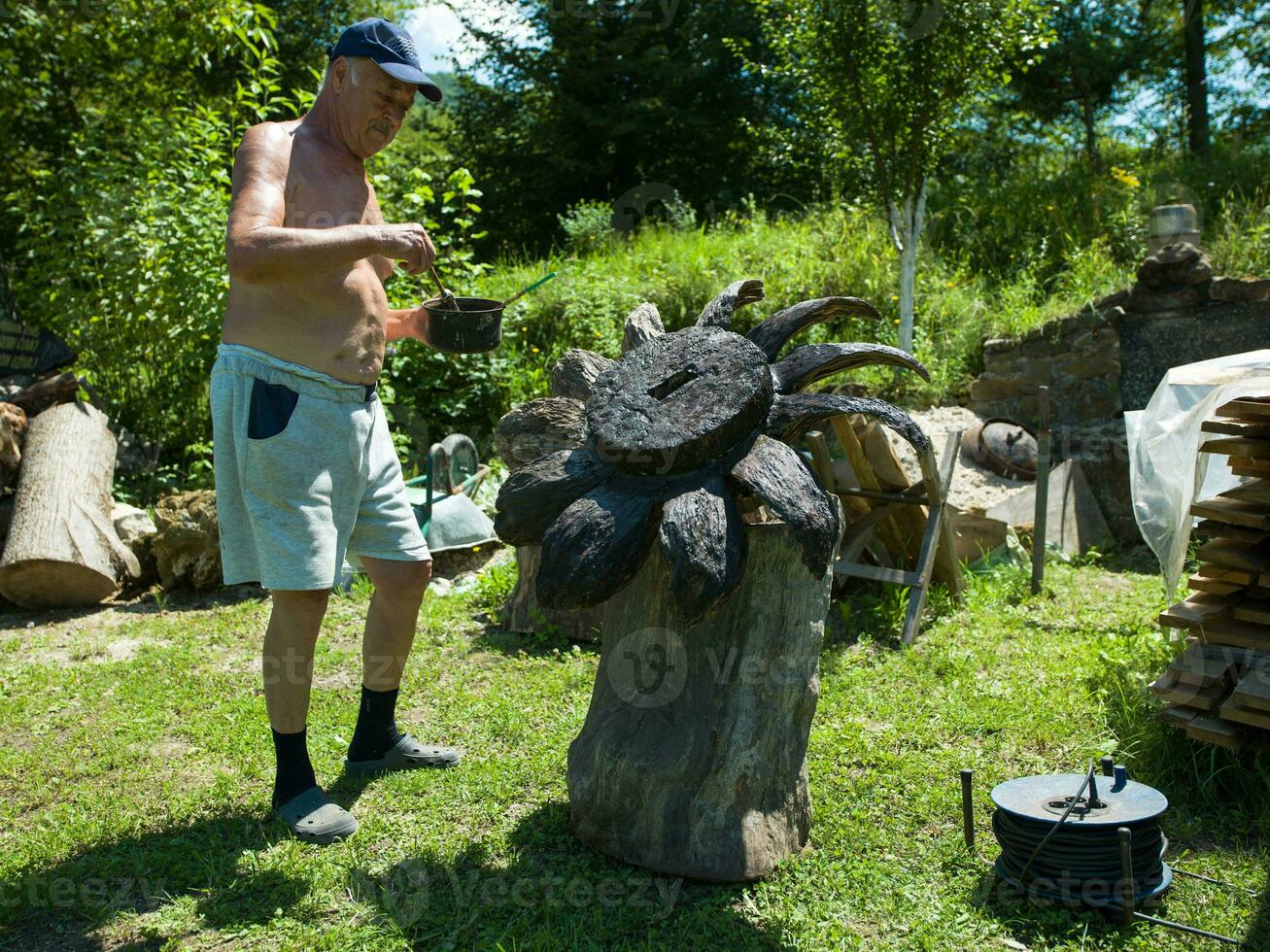 alt Senior Mann mit ausdrucksvoll Gesicht Gemälde vorsichtig ein Garten Kunst Skulptur foto
