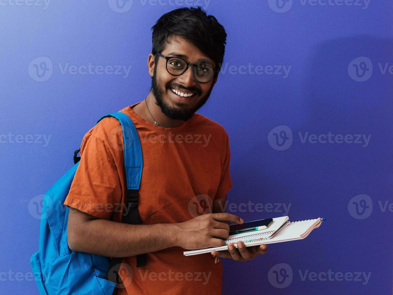 indisch Schüler mit Blau Rucksack, Brille und Notizbuch posieren auf lila Hintergrund. das Konzept von Bildung und Schulung. Zeit zu gehen zurück zu Schule foto