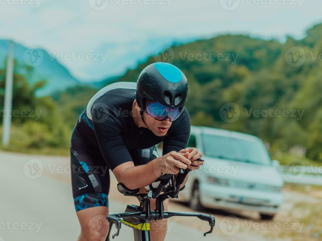 voll Länge Porträt von ein aktiv Triathlet im Sportbekleidung und mit ein schützend Helm Reiten ein Fahrrad. selektiv Fokus foto