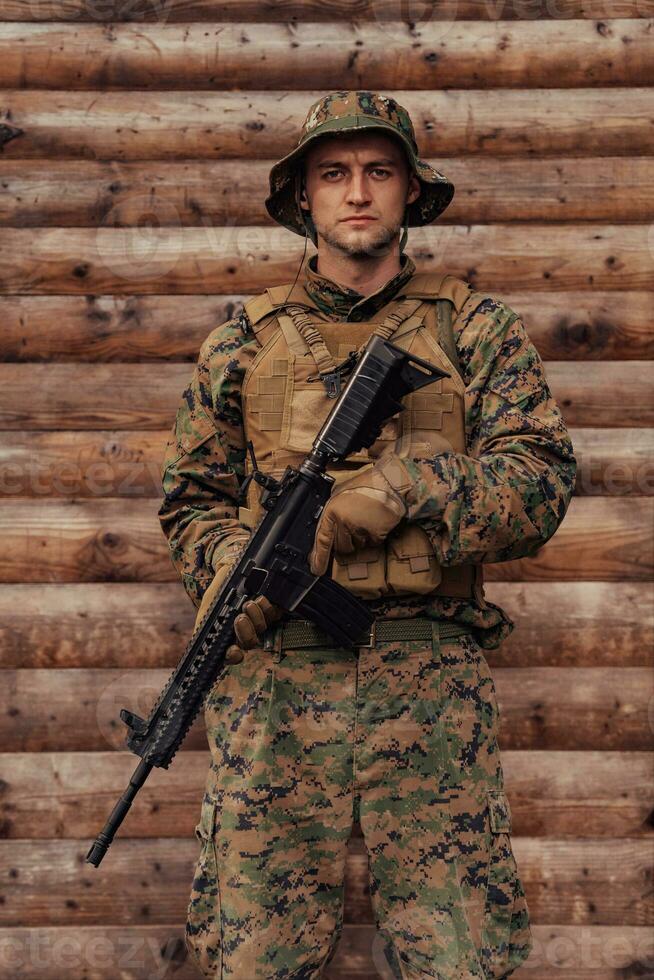 ein Soldat im Uniform mit ein Gewehr im seine Hand ist Stehen im Vorderseite von ein hölzern Mauer. ein Soldat Wachen das Wald Base von das Feind foto