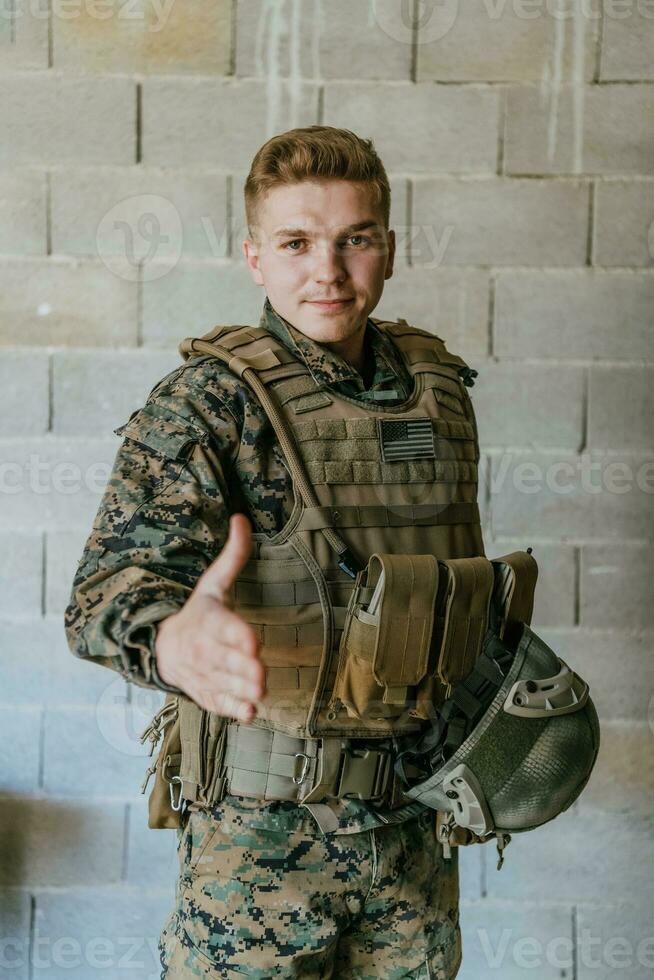 ein Soldat im Uniform steht im Vorderseite von ein Stein Mauer mit ein ausgestreckt Hand. das Konzept von Militär- und Krieg Partnerschaft foto