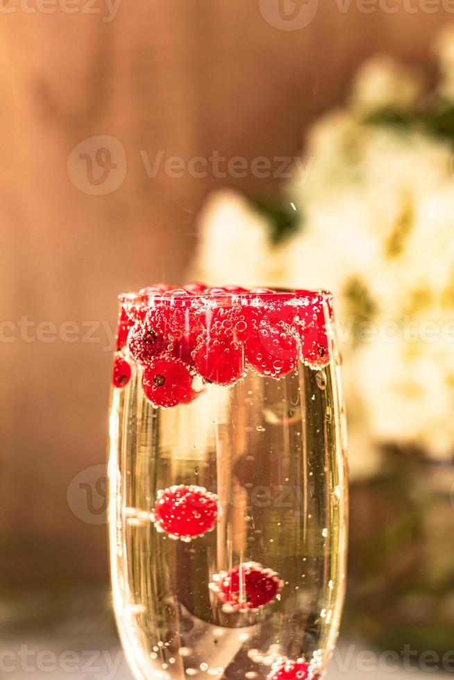 Sekt im Glas mit roten Johannisbeeren foto